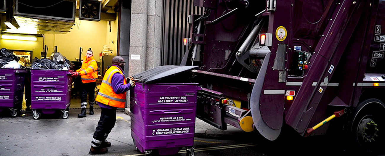 Simply Waste Solutions driver pushing wheelie bin up to trade waste truck ready to be tipped